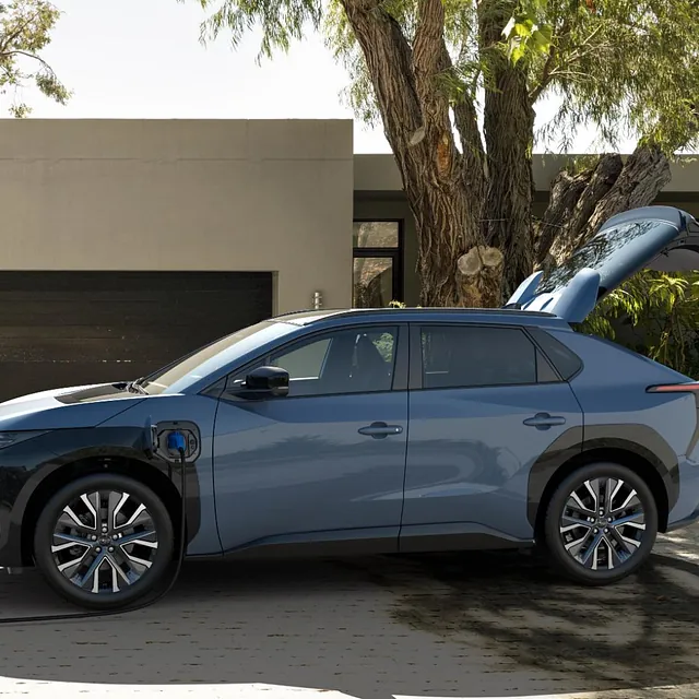 Solterra står parkert med bakluke åpen og ladekabel tilkoblet foran moderne bolig.