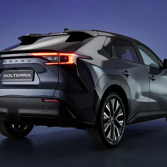 Baklys og detaljer vises på mørk Subaru Solterra parkert i studio med lilla bakgrunn.